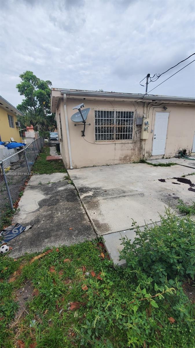 The exterior of a single-story house features a concrete patio, a window with security bars, and a satellite dish — 2980 NW 91st St # 1, Miami FL 33147, MIAMI, FL