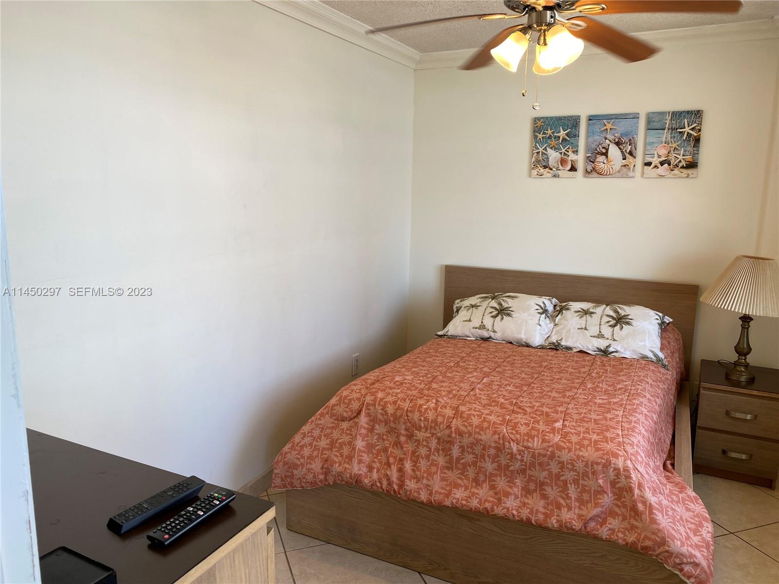 A bedroom features a bed with a palm-print quilt, a wooden headboard, and a ceiling fan — 3725 S Ocean Dr # 1521, Hollywood FL 33019, HOLLYWOOD, FL