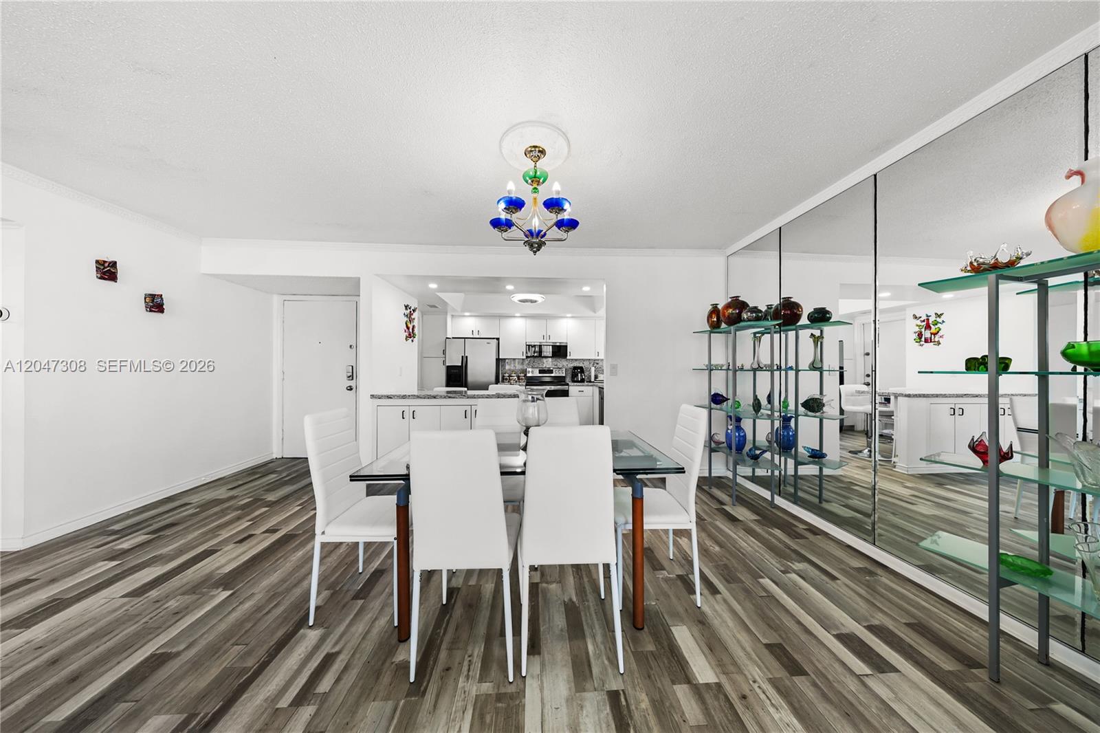 A dining area features a glass table, white chairs, wood-look flooring, and a mirrored wall — 1825 S Ocean Dr # 914, Hallandale Beach FL 33009, HALLANDALE BEACH, FL