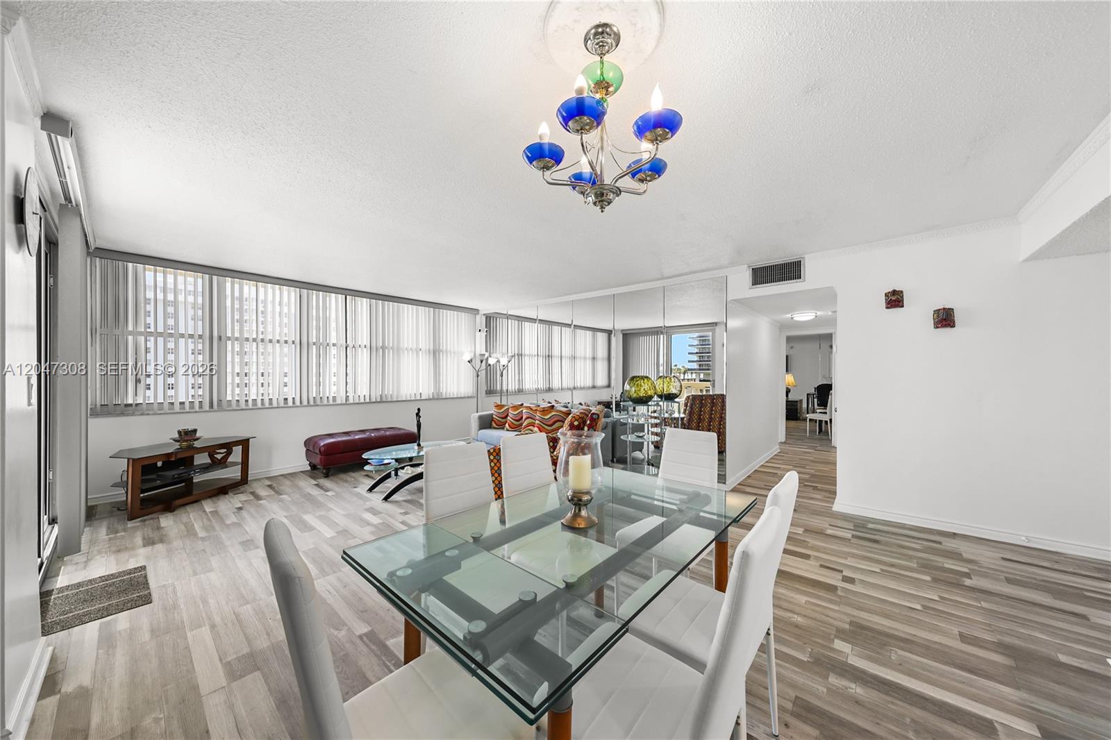 A dining area with a glass table and white chairs opens into a living room — 1825 S Ocean Dr # 914, Hallandale Beach FL 33009, HALLANDALE BEACH, FL
