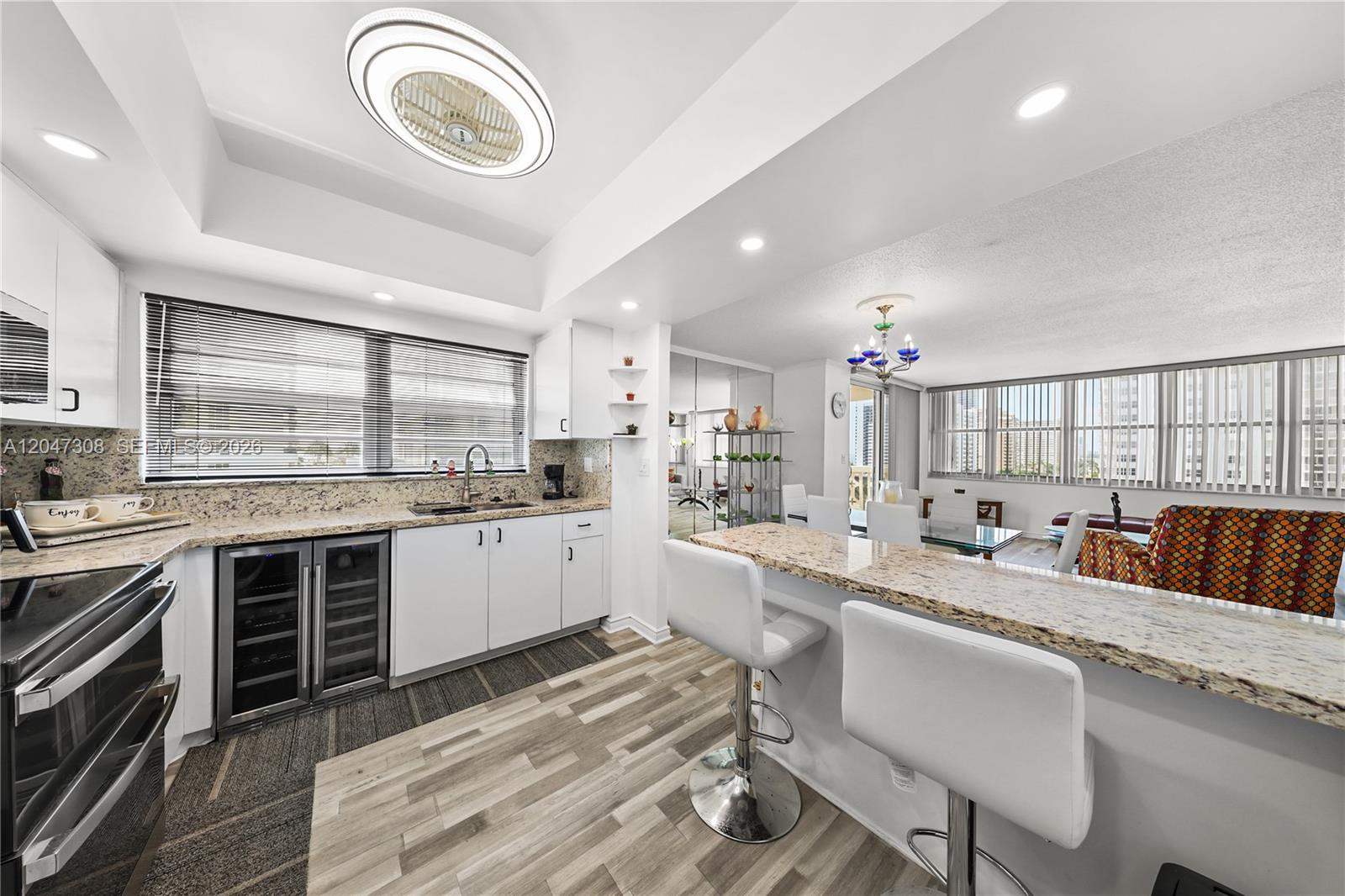 A kitchen with white cabinets, granite countertops, and a breakfast bar overlooks a dining area — 1825 S Ocean Dr # 914, Hallandale Beach FL 33009, HALLANDALE BEACH, FL
