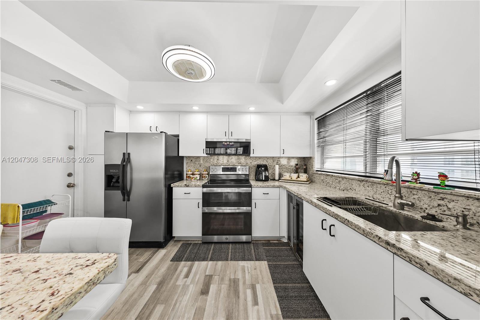 A kitchen features white cabinets, granite countertops, stainless steel appliances, and wood-look flooring — 1825 S Ocean Dr # 914, Hallandale Beach FL 33009, HALLANDALE BEACH, FL