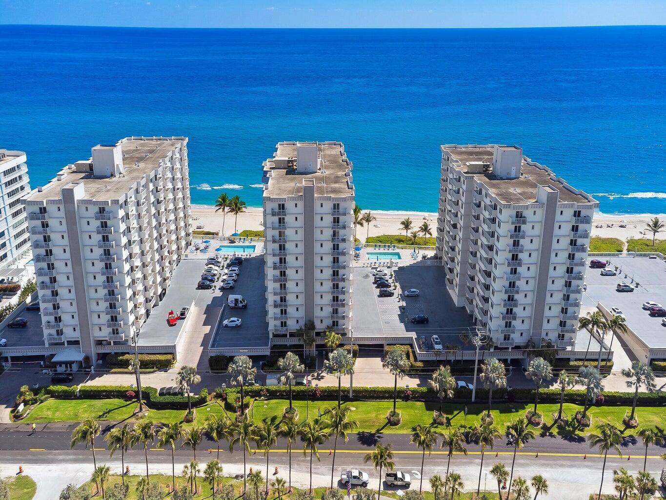 An aerial view shows three beachfront apartment buildings with parking lots and a swimming pool — 3215 S Ocean Boulevard # 303, Highland Beach FL 33487, HIGHLAND BEACH, FL