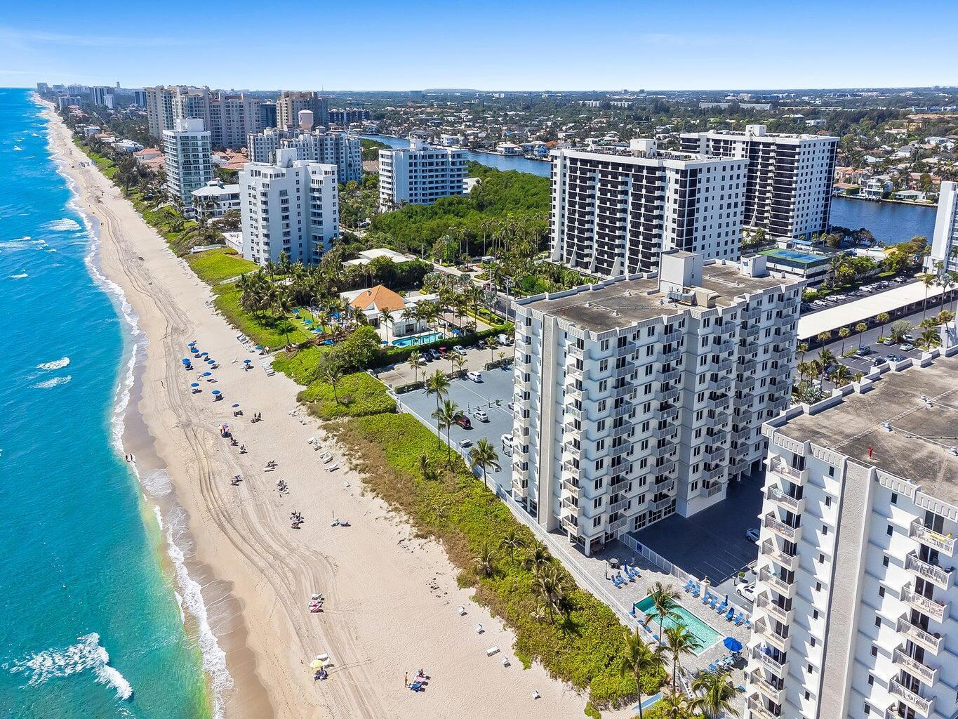 An aerial view of a sandy beach lined with high-rise residential buildings and palm trees — 3215 S Ocean Boulevard # 303, Highland Beach FL 33487, HIGHLAND BEACH, FL