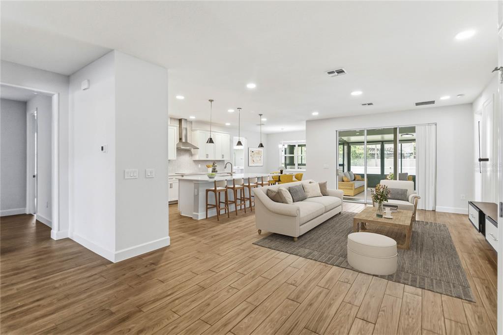 An open-concept living room and kitchen featuring light wood-look flooring and a sliding glass door — 2510 CEDAR SHAKE COURT, OVIEDO, FL
