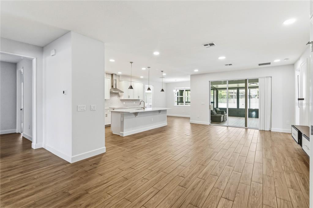 An open-concept kitchen and living area features light wood-look tile flooring and white cabinetry — 2510 CEDAR SHAKE COURT, OVIEDO, FL