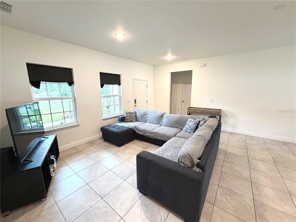 A living room features light tile flooring, a large sectional sofa, and two windows — 835 MARION OAKS MANOR, OCALA, FL