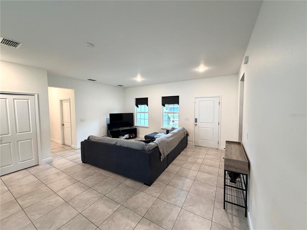 A living room features light tile flooring, white walls, a large sectional sofa, and two windows — 835 MARION OAKS MANOR, OCALA, FL