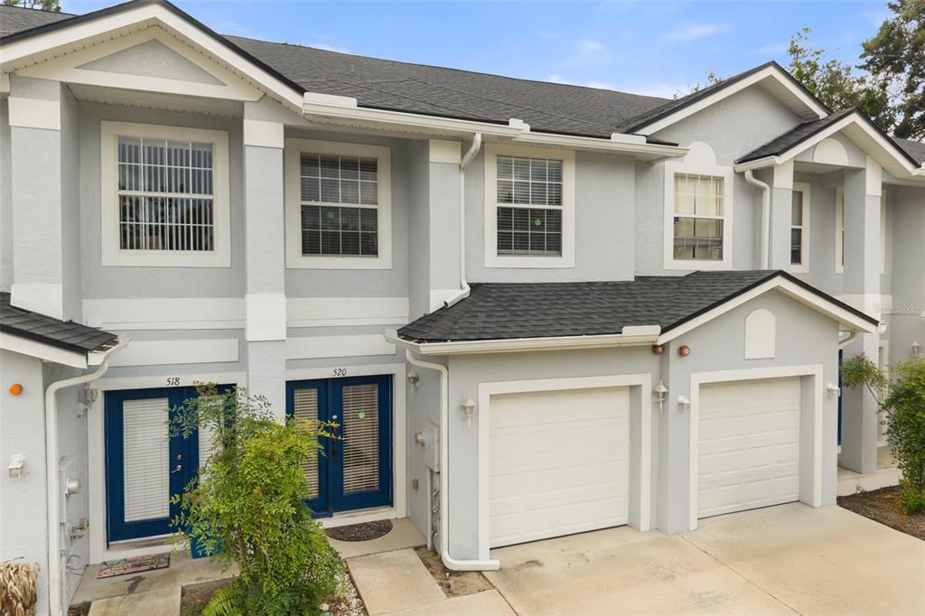 An exterior view of a two-story townhouse with light gray siding and two garage doors — 520 MAJESTIC WAY, ALTAMONTE SPRINGS, FL