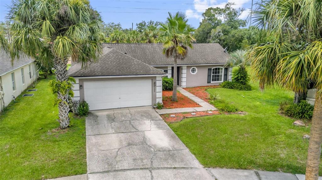 An exterior view of a single-story house with a two-car garage and palm trees — 14520 LYCASTLE CIRCLE, ORLANDO, FL
