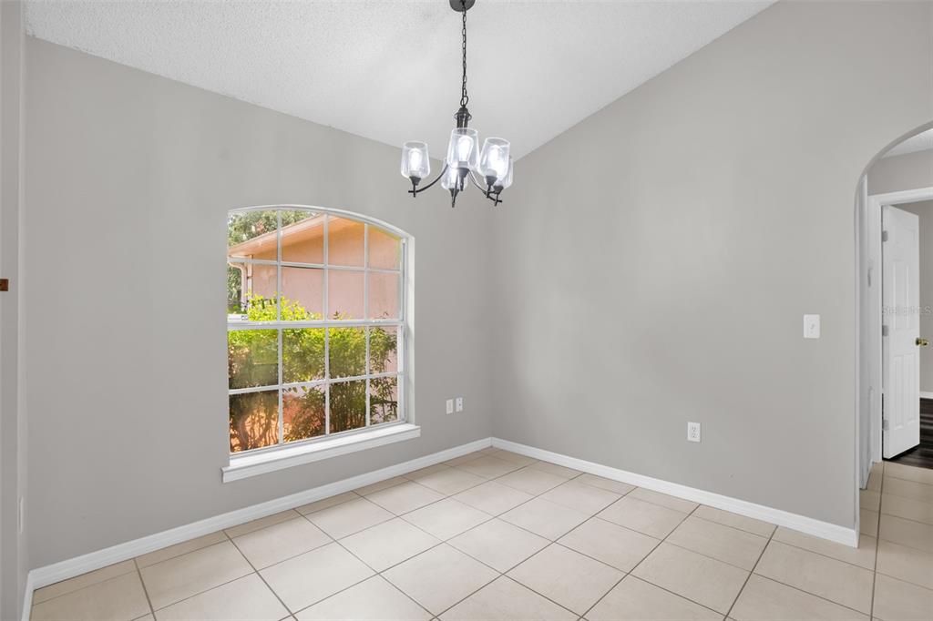 A dining area with light gray walls, tile flooring, a chandelier, and an arched window — 14520 LYCASTLE CIRCLE, ORLANDO, FL