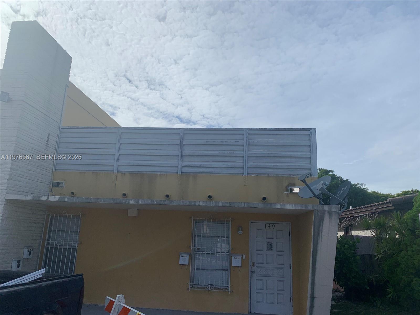 A two-story yellow building exterior features a white metal balcony railing and a front door — 149 Bentley Dr # 149A, Miami Springs FL 33166, MIAMI SPRINGS, FL