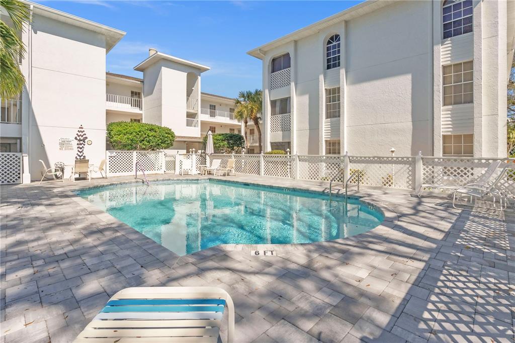 A swimming pool sits in a courtyard surrounded by white multi-story apartment buildings — 6304 POINTE WEST BOULEVARD UNIT A107, BRADENTON, FL