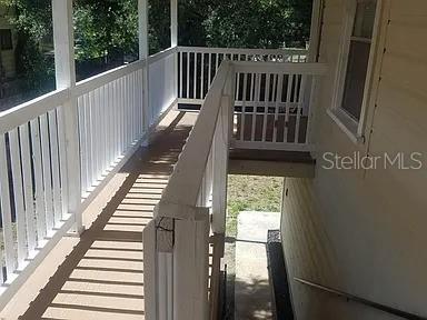 An elevated wooden deck with white railings overlooks a concrete staircase and a grassy yard — 114 W WILDER AVENUE, TAMPA, FL