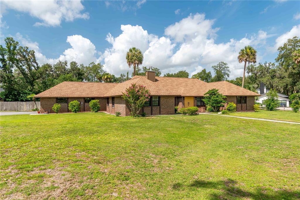A single-story brick house with a brown shingled roof sits on a large grassy lot — 3555 SW 24TH AVENUE ROAD, OCALA, FL