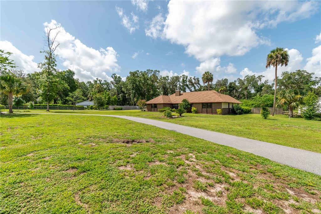 A single-story brick house with a brown shingled roof sits on a large grassy lot — 3555 SW 24TH AVENUE ROAD, OCALA, FL