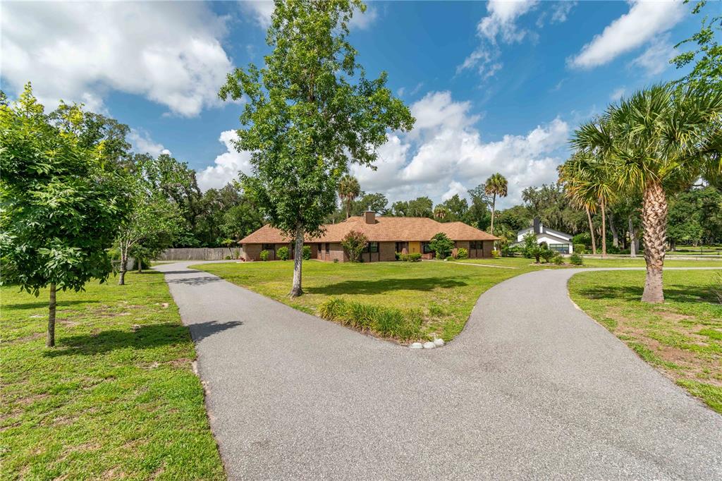 A single-story brick house with a brown shingled roof sits behind a split paved driveway — 3555 SW 24TH AVENUE ROAD, OCALA, FL