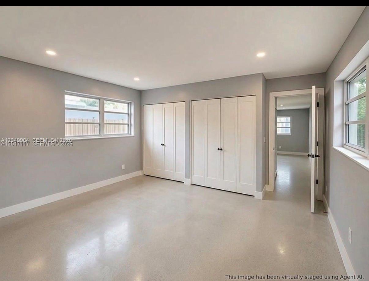 An empty bedroom with gray walls, white closet doors, and polished concrete flooring — 1140 NE 24th Ave # 1, Pompano Beach FL 33062, POMPANO BEACH, FL