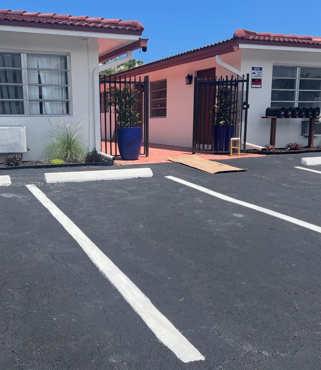 An exterior view of a building with a parking lot and a gated courtyard entrance — 1140 NE 24th Ave # 1, Pompano Beach FL 33062, POMPANO BEACH, FL