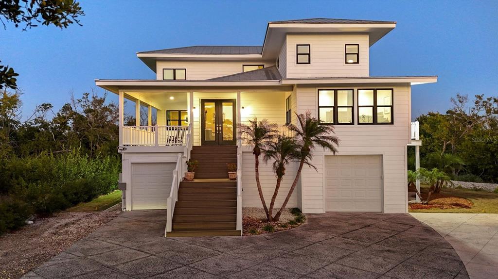 A two-story white house with a raised porch, stairs, and two ground-level garage doors — 5010 GROUPER HOLE COURT, BOCA GRANDE, FL