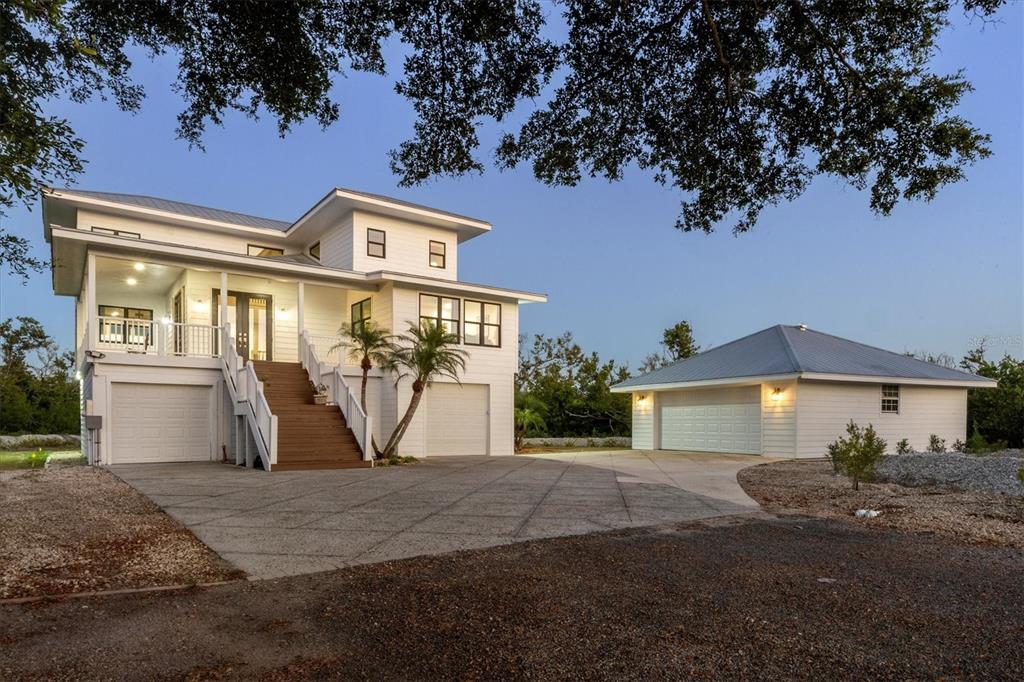 A white two-story house with a detached garage and a concrete driveway at dusk — 5010 GROUPER HOLE COURT, BOCA GRANDE, FL