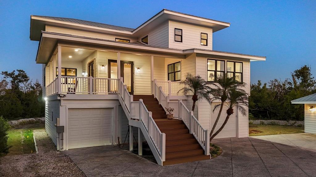A two-story white house with a raised porch, central staircase, and two garage doors — 5010 GROUPER HOLE COURT, BOCA GRANDE, FL