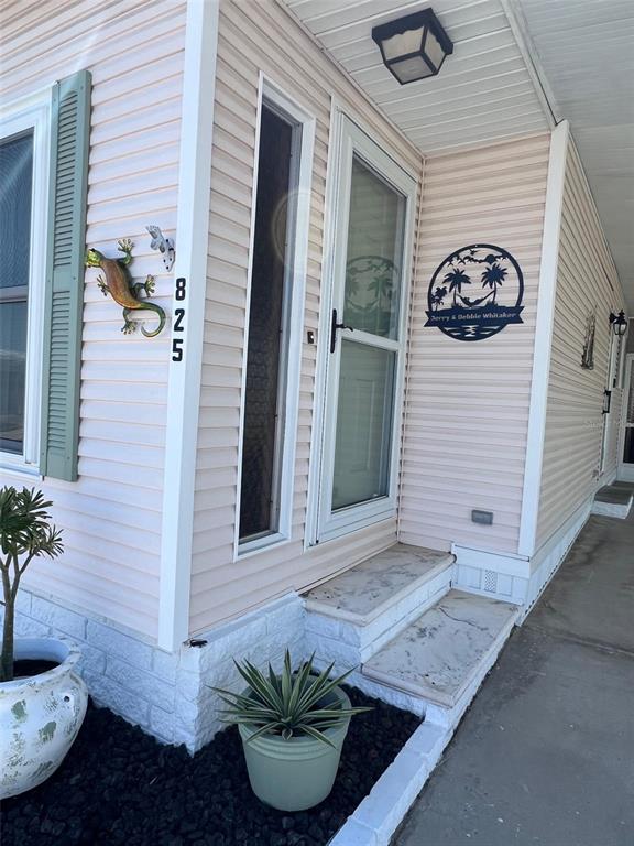 The exterior of a light pink mobile home features a front door, steps, and decor — 825 COCONUT PALM STREET, LARGO, FL