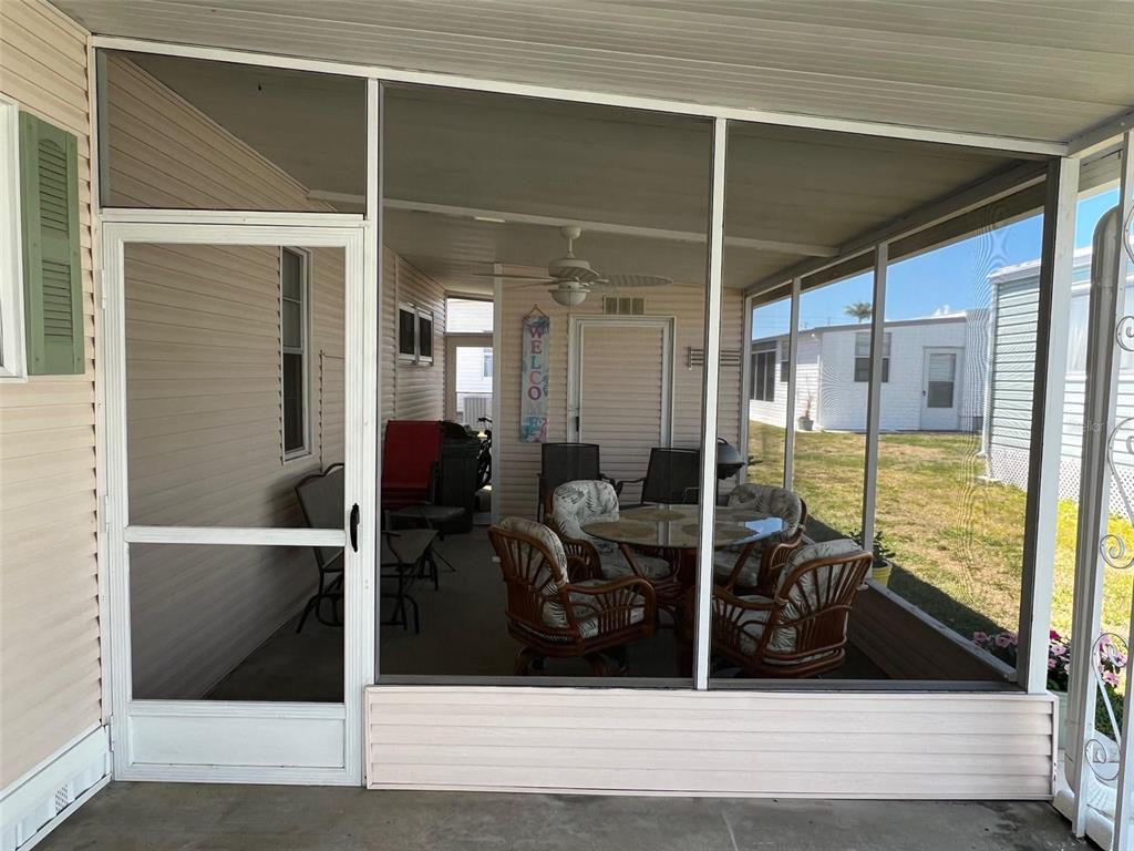 A screened-in porch features a white door, wicker furniture, and a ceiling fan — 825 COCONUT PALM STREET, LARGO, FL