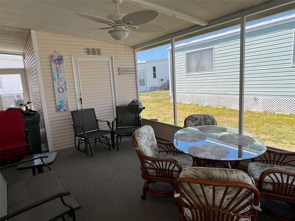 A screened-in porch features a glass-topped dining table, several chairs, and a ceiling fan — 825 COCONUT PALM STREET, LARGO, FL
