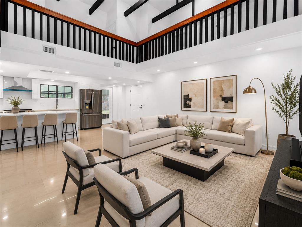A living room with a wooden staircase, black railings, and high ceilings with exposed beams — 4221 GREENFERN DRIVE, ORLANDO, FL