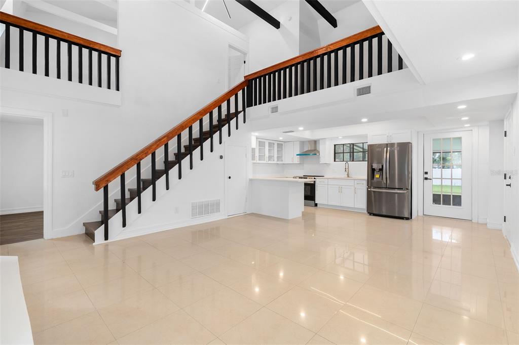 A bright, open-concept kitchen and living area features high ceilings, tile floors, and a loft — 4221 GREENFERN DRIVE, ORLANDO, FL