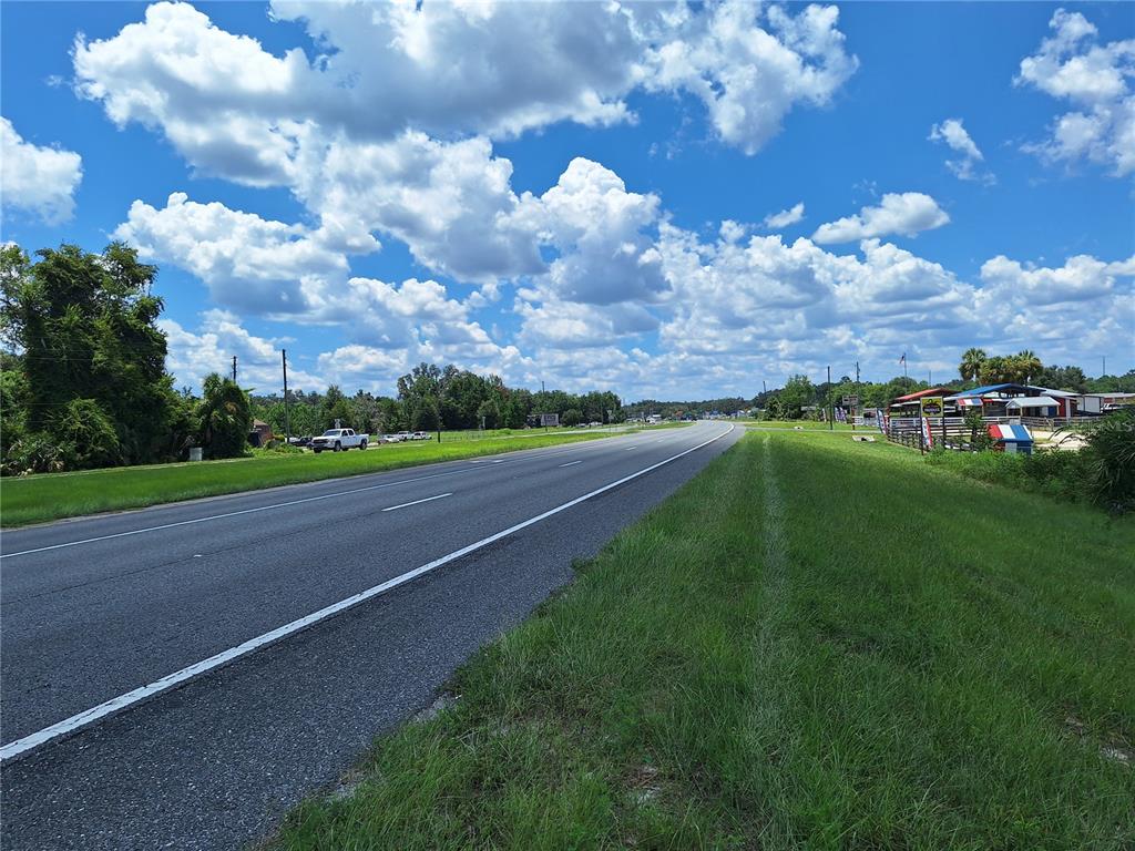 A paved road stretches into the distance under a bright blue sky with scattered clouds — TBD SE HWY. 19, OLD TOWN, FL