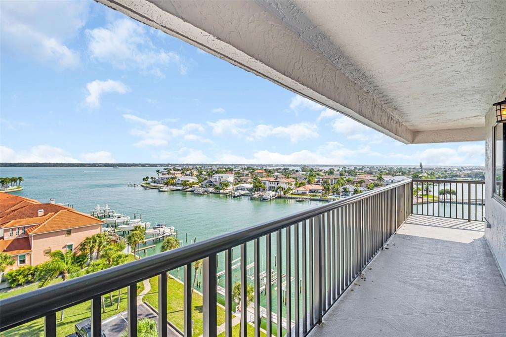 A balcony with a metal railing overlooks a waterfront residential area with boats and docks — 1651 SAND KEY ESTATES CT UNIT 74, CLEARWATER BEACH, FL