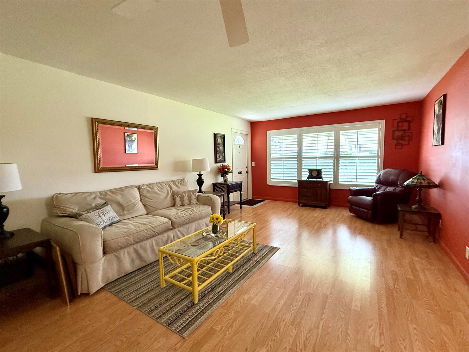 A living room features light wood flooring, a beige sofa, a yellow coffee table, and red walls — 215 South Boulevard # C, Boynton Beach FL 33435, BOYNTON BEACH, FL
