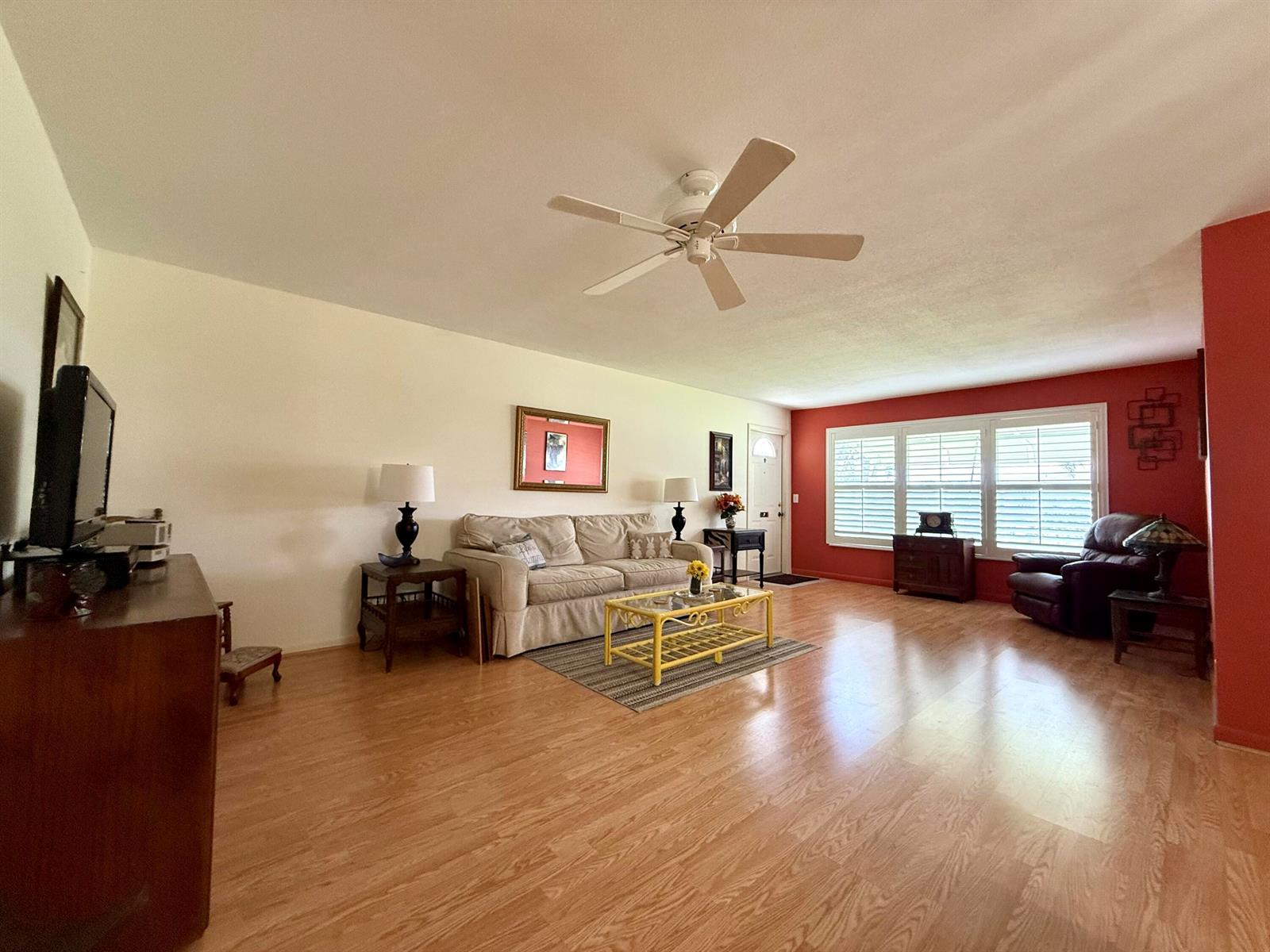 A living room features light wood flooring, a beige sofa, and a red accent wall — 215 South Boulevard # C, Boynton Beach FL 33435, BOYNTON BEACH, FL