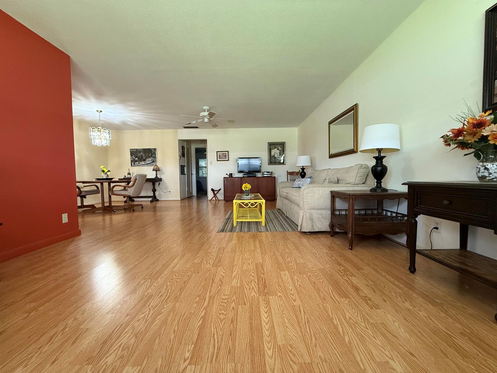 A living room with light wood flooring, a red accent wall, and a dining area — 215 South Boulevard # C, Boynton Beach FL 33435, BOYNTON BEACH, FL