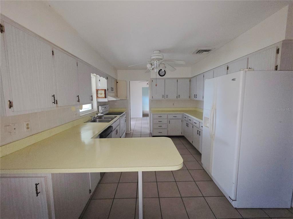 A kitchen features white cabinets, yellow laminate countertops, tile flooring, and a white refrigerator — 416 6TH ST S, DUNDEE, FL