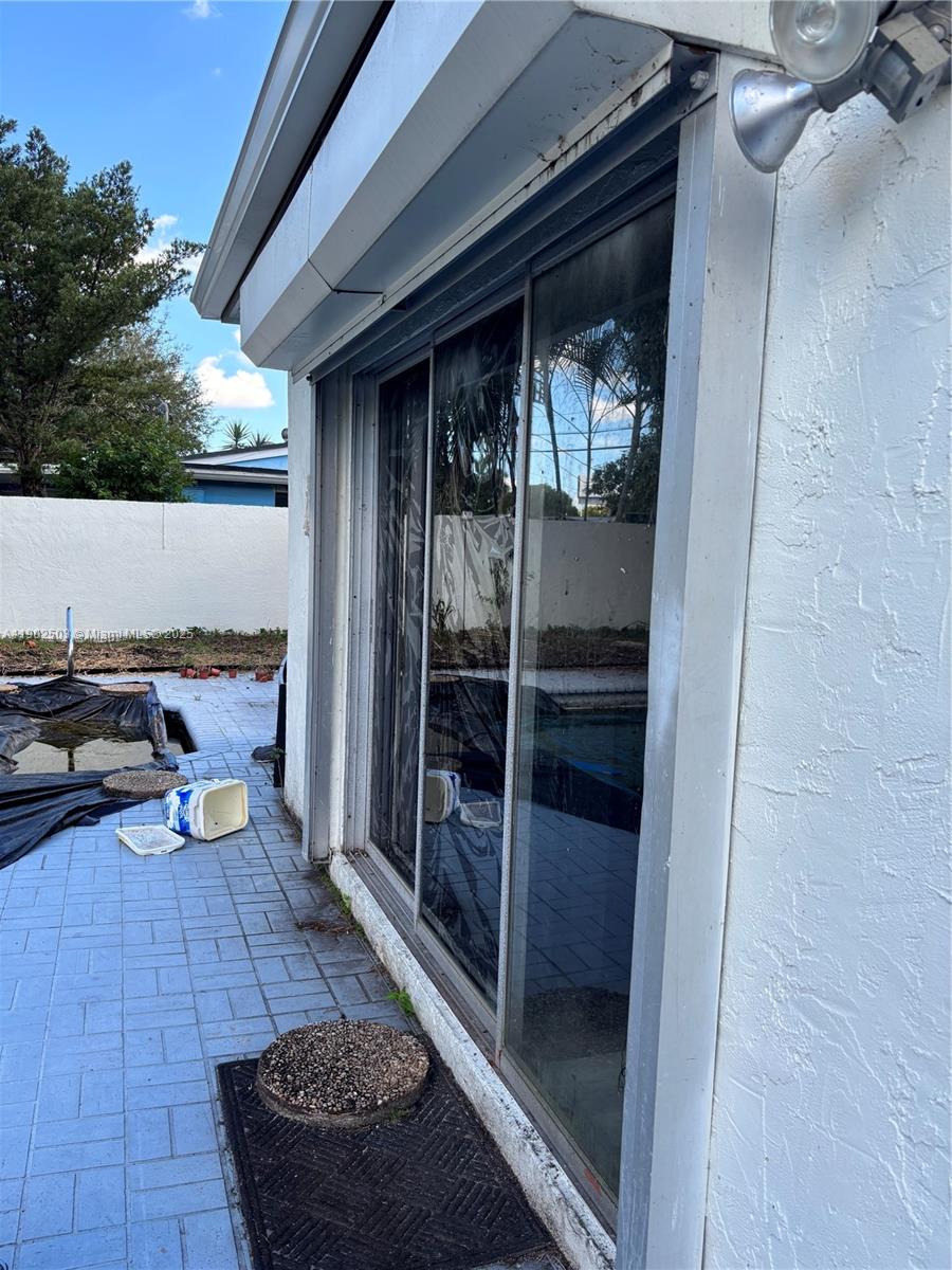 A sliding glass door opens onto a patio with a pool and paved deck — 6541 Sherman St, Hollywood FL 33024, HOLLYWOOD, FL