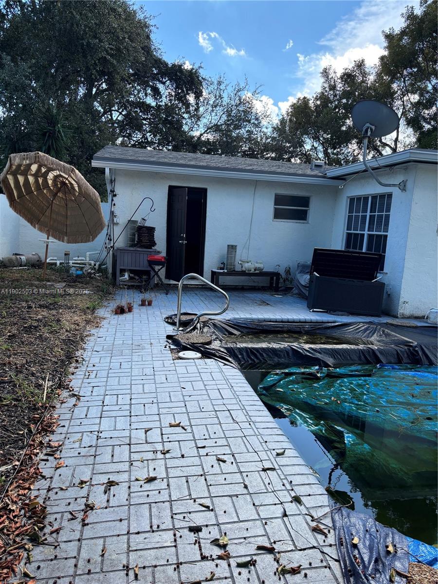 A backyard features a swimming pool with a cover, a patio, and a white house — 6541 Sherman St, Hollywood FL 33024, HOLLYWOOD, FL