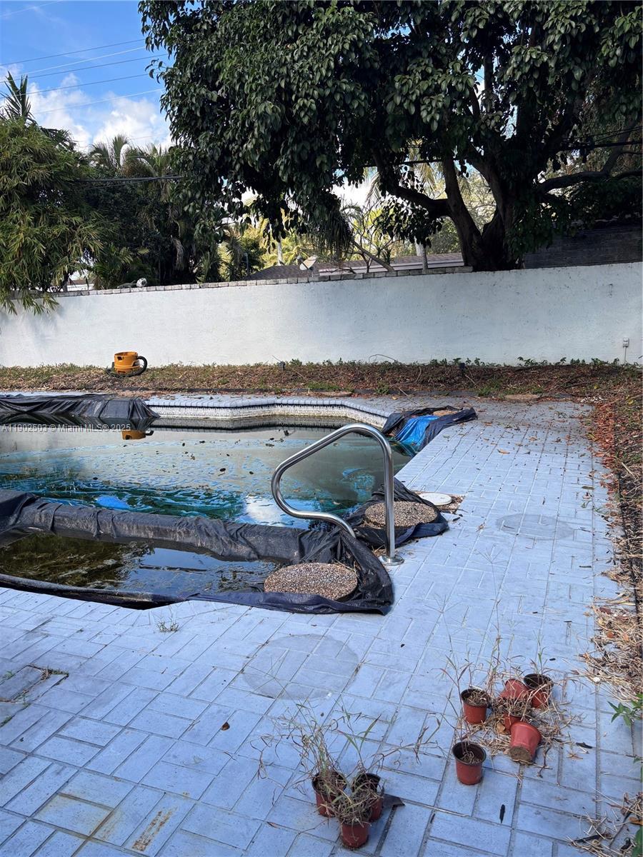 An outdoor swimming pool with a partial cover and surrounding brick patio — 6541 Sherman St, Hollywood FL 33024, HOLLYWOOD, FL