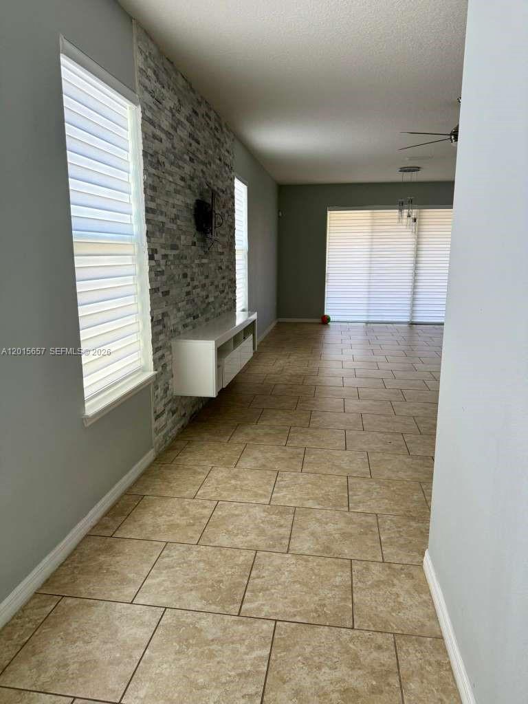 A living room features a stone accent wall, white floating console, and tiled flooring — 173 Tracy Circle, Winter Haven FL 33884, WINTER HAVEN, FL