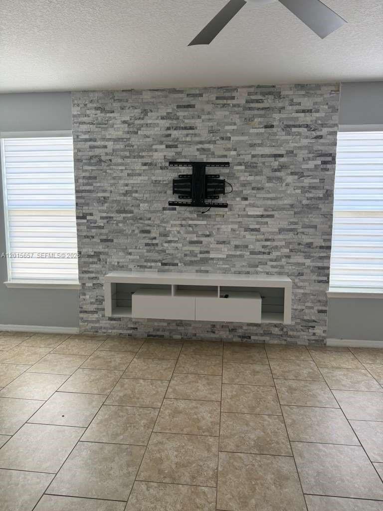 A living room features a stone-tiled accent wall with a mounted TV bracket and console — 173 Tracy Circle, Winter Haven FL 33884, WINTER HAVEN, FL