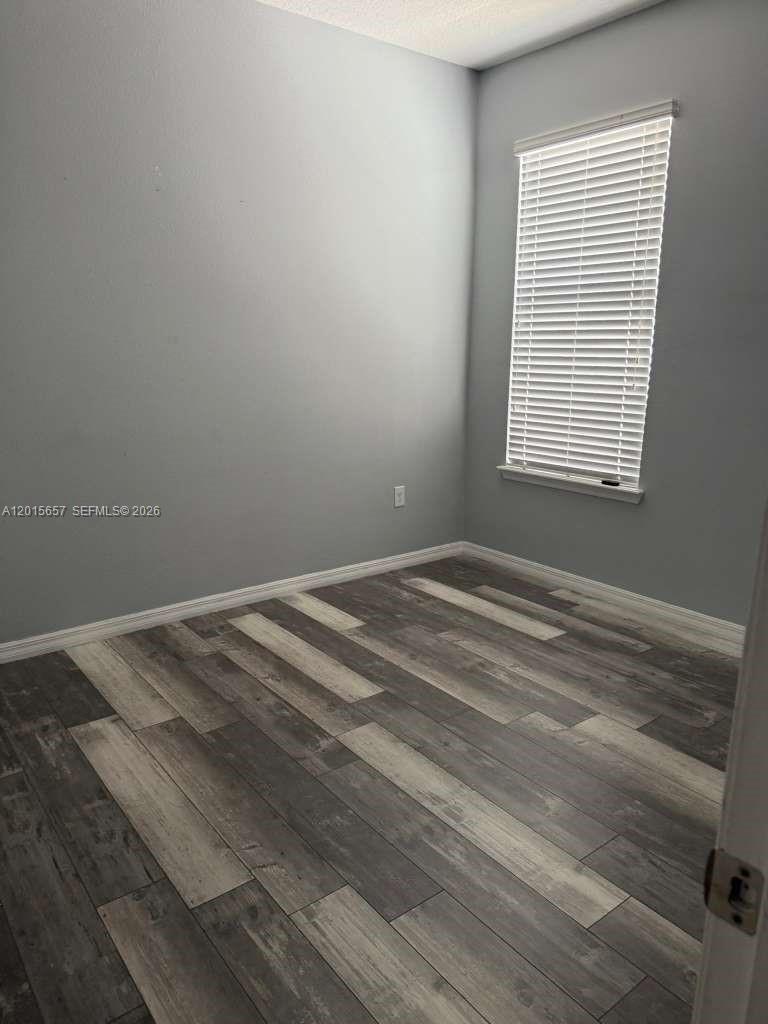 An empty room features light gray walls, wood-look plank flooring, and a window with blinds — 173 Tracy Circle, Winter Haven FL 33884, WINTER HAVEN, FL