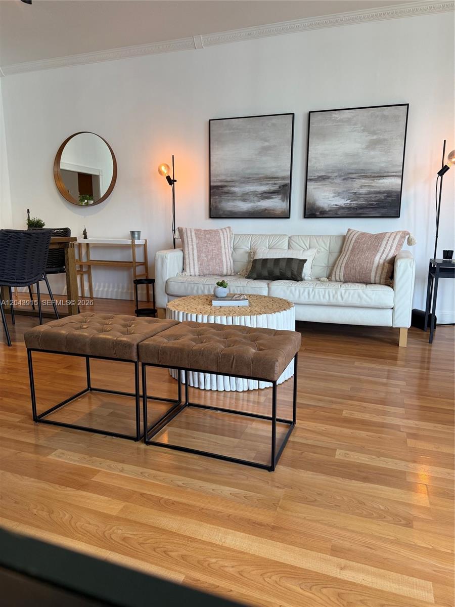 A living room features a white sofa, two brown ottomans, and two abstract wall paintings — 520 Brickell Key Dr # A1412, Miami FL 33131, MIAMI, FL