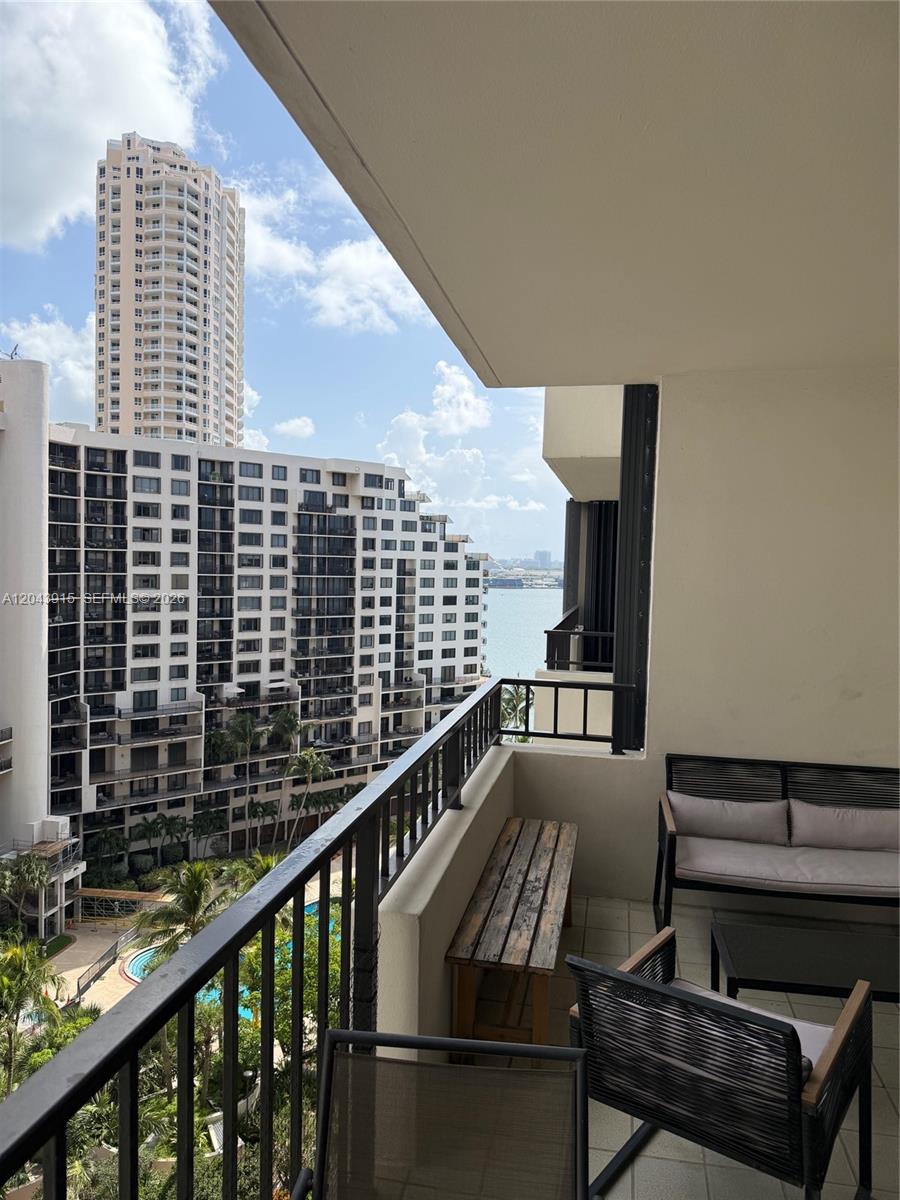 A balcony with outdoor furniture overlooks a large apartment complex and a body of water — 520 Brickell Key Dr # A1412, Miami FL 33131, MIAMI, FL
