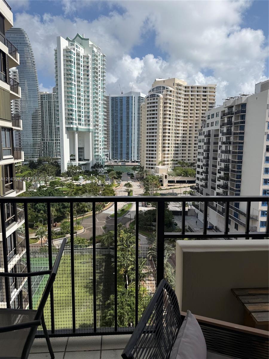 A balcony view overlooks a landscaped park surrounded by several high-rise apartment buildings — 520 Brickell Key Dr # A1412, Miami FL 33131, MIAMI, FL