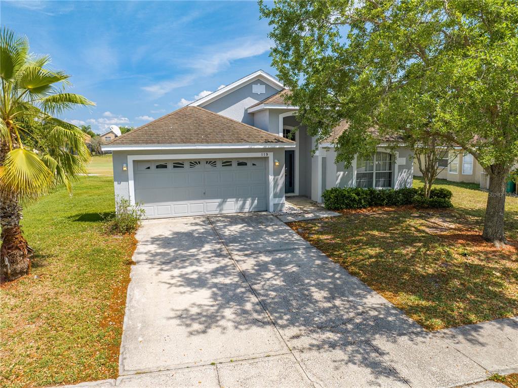 A single-story house with a gray exterior, a two-car garage, and a concrete driveway — 119 SOUTHAMPTON DRIVE, KISSIMMEE, FL