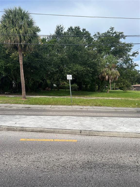 A vacant, grassy lot with trees and a sidewalk is viewed from across the street — MARTIN LUTHER KING JR AVENUE, CLEARWATER, FL