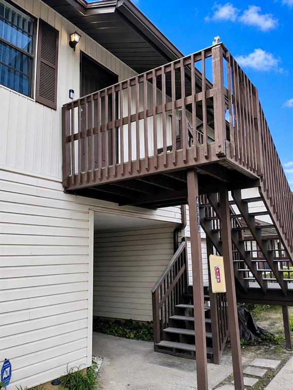 An exterior view of a two-story building featuring a wooden staircase and balcony — 4973 91ST AVENUE UNIT 12 (C), PINELLAS PARK, FL