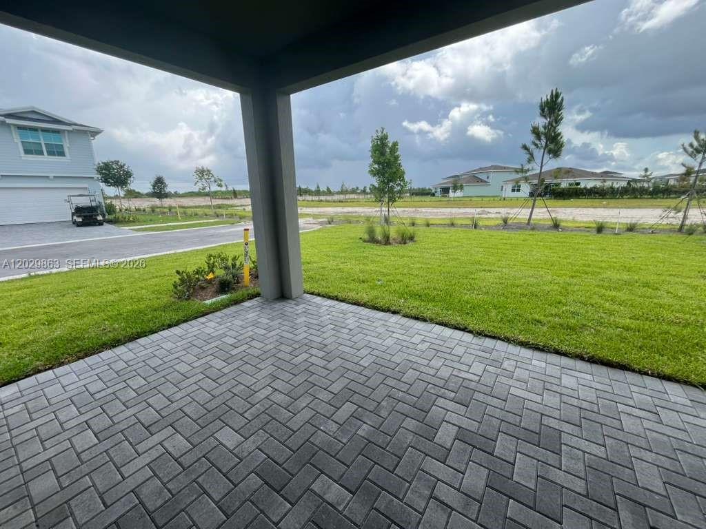 A covered patio with gray brick pavers overlooks a grassy yard and neighborhood houses — 19788 Whispering Creek Rd # 19788, Loxahatchee FL 33470, LOXAHATCHEE, FL